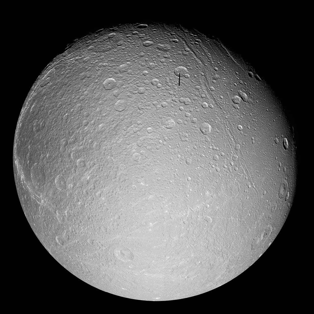 Cassini grayscale full-disk mosaic of Dione showing bright icy terrain, craters and long fractures.