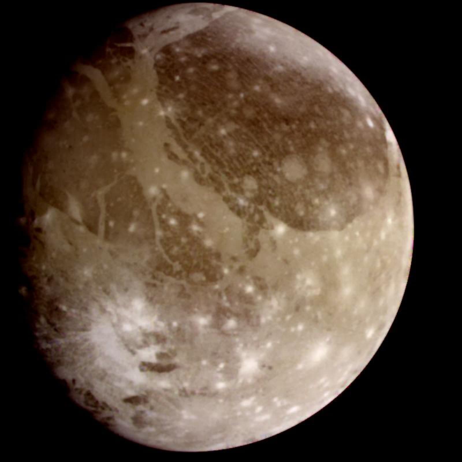 Natural-color Galileo view of Ganymede with dark ancient terrain, bright grooves and impact scars.