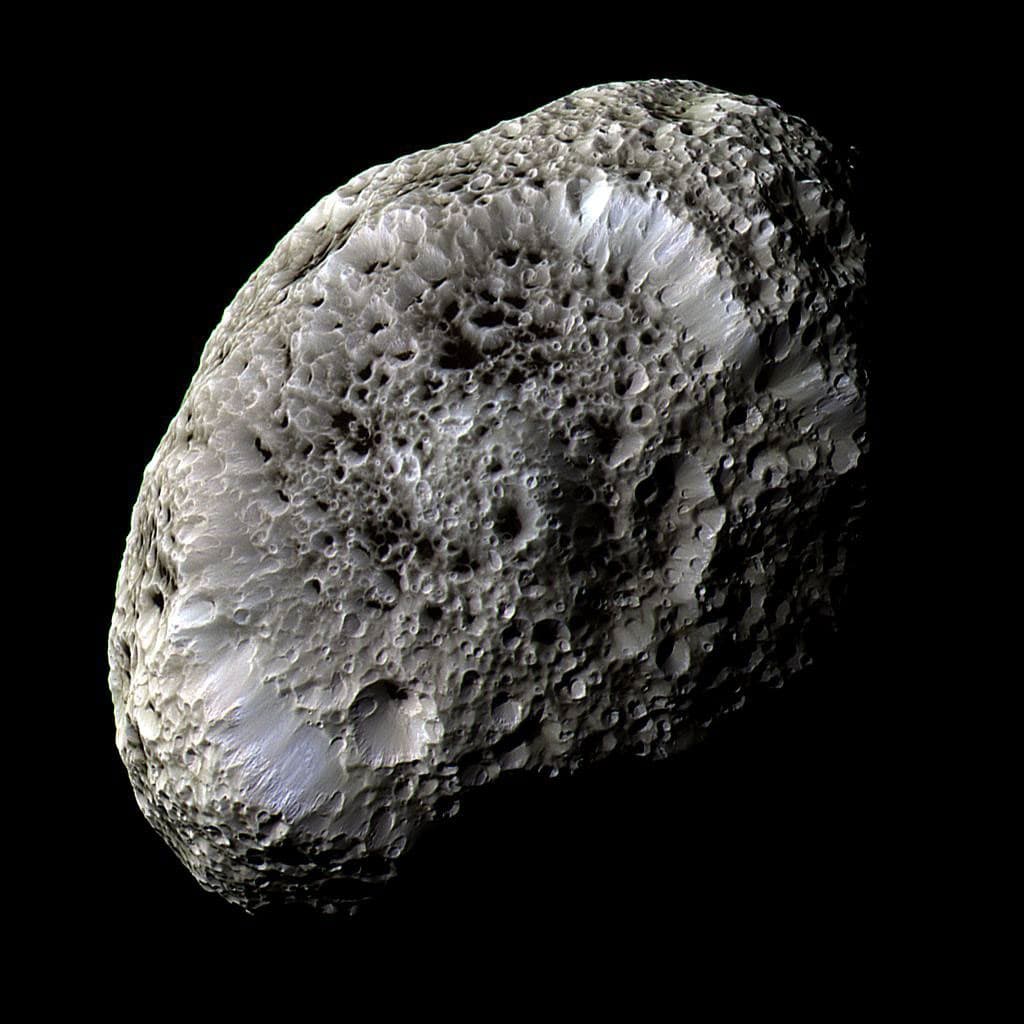Cassini false-color view of irregular Hyperion, covered in deep sponge-like craters with bright walls and dark floors.
