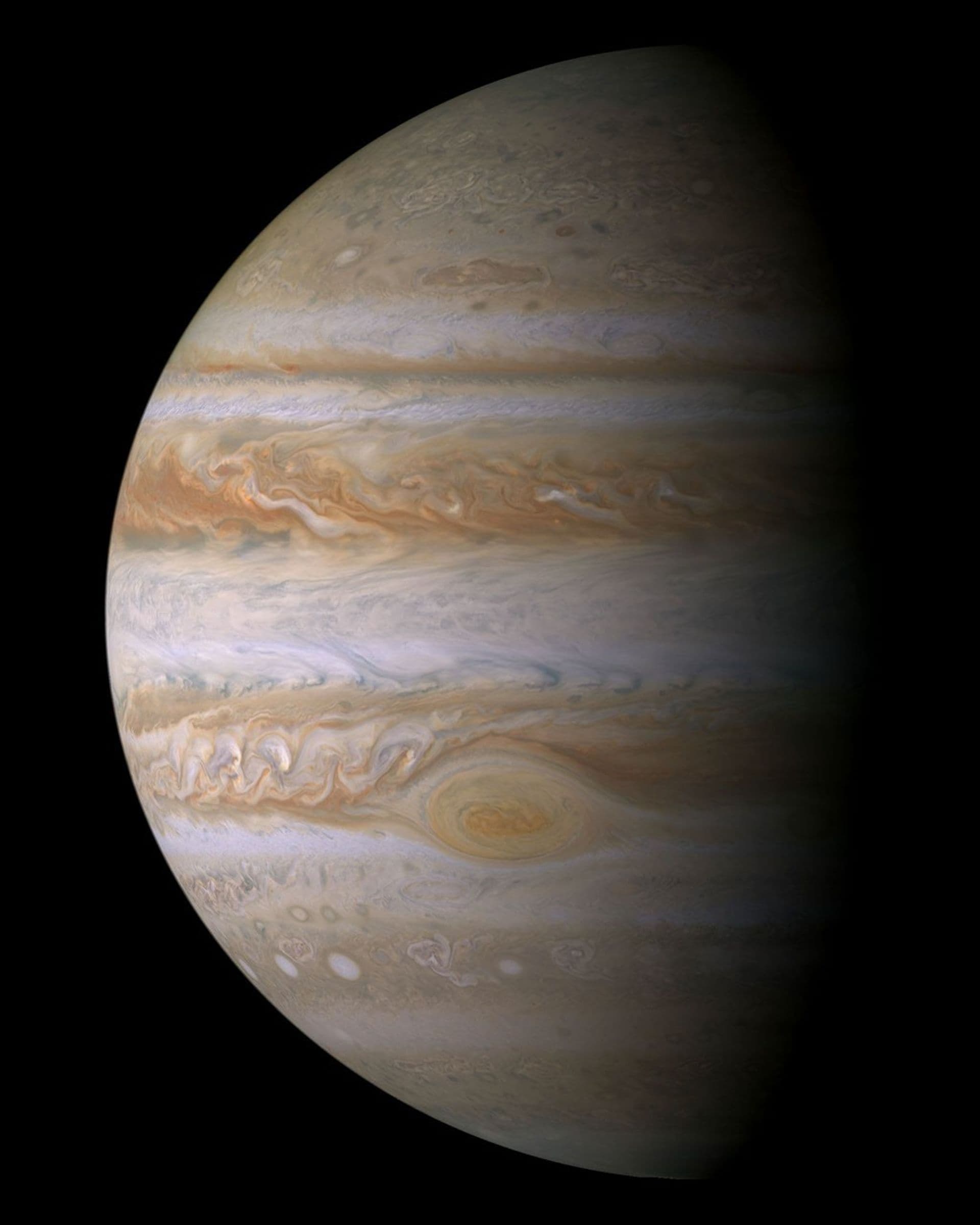 A near-natural-color global mosaic of Jupiter showing cream and reddish cloud bands, white ovals and the Great Red Spot.