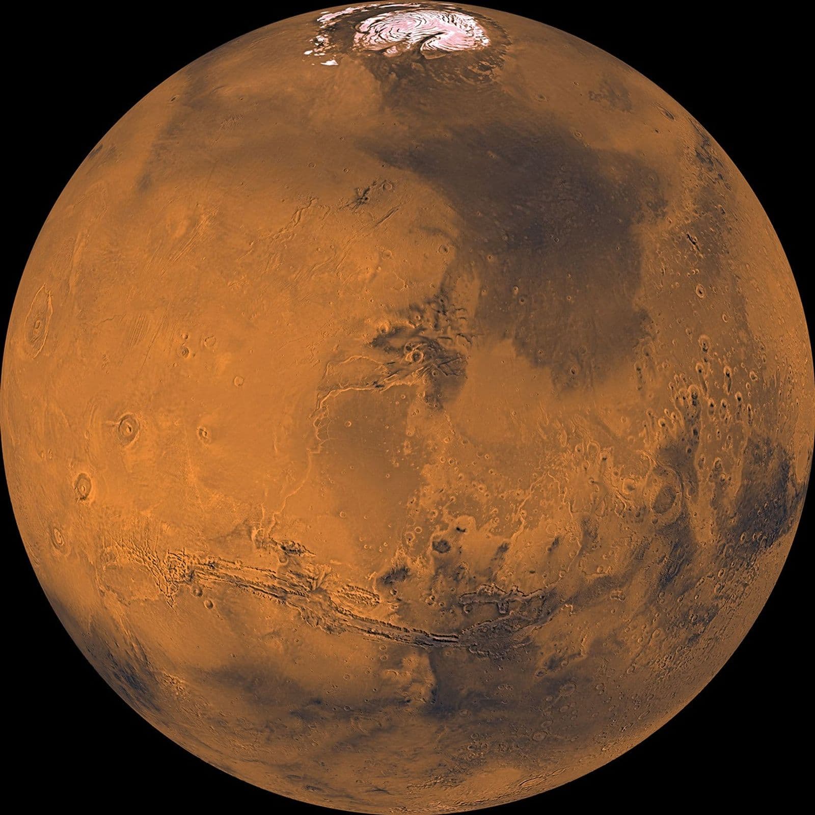 A processed global color mosaic of Mars with reddish terrain, a bright north polar cap, dark regions and Valles Marineris.