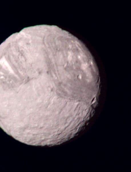 Voyager 2 color composite of Miranda showing bright and dark banded terrain, craters, ridges and valleys.
