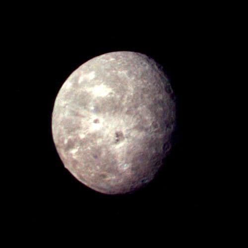 Voyager 2 reconstructed-color image of Oberon with bright-ray craters, dark crater floors and a mountain at the limb.