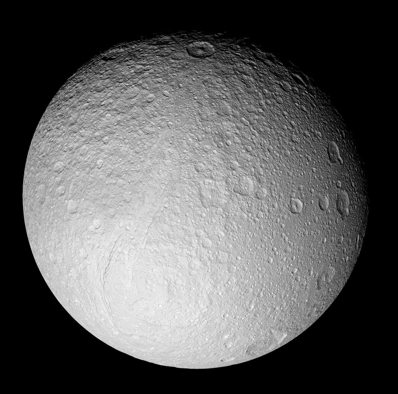 Cassini grayscale mosaic of Tethys showing its bright cratered disk and the long Ithaca Chasma fracture system.