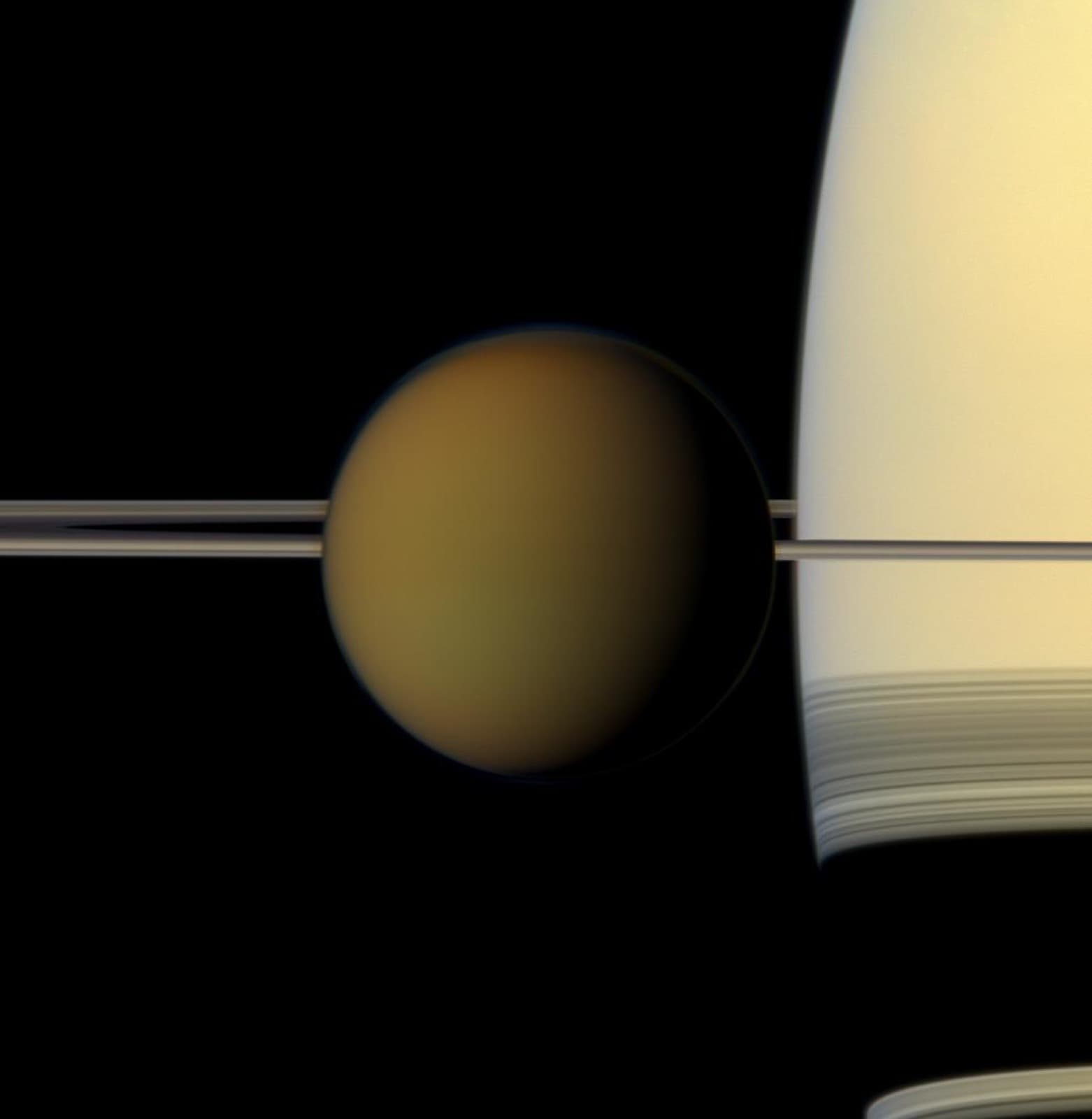 Natural-color Cassini view of hazy orange Titan passing in front of Saturn and its rings.