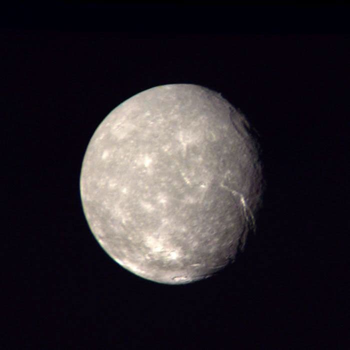 Voyager 2 color composite of Titania showing craters and a large trench near the day-night boundary.