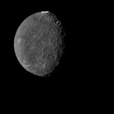 Voyager 2 clear-filter image of dark Umbriel with heavy cratering and a bright ring near the limb.